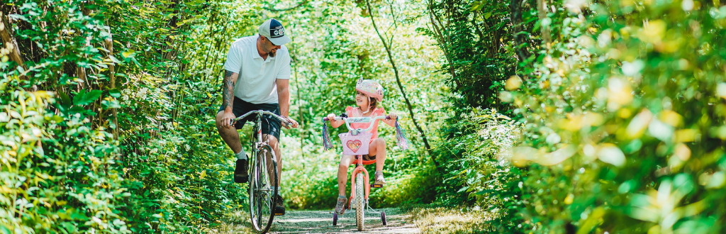 father and daughter biking on the trail