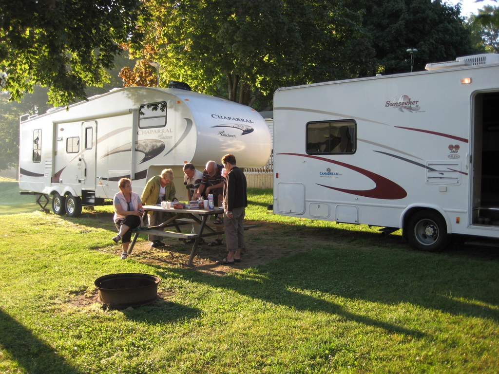 A family having a picnic with RVs in the back 