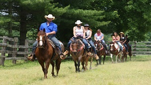 people riding horses through the stable at texas longhorn ranch