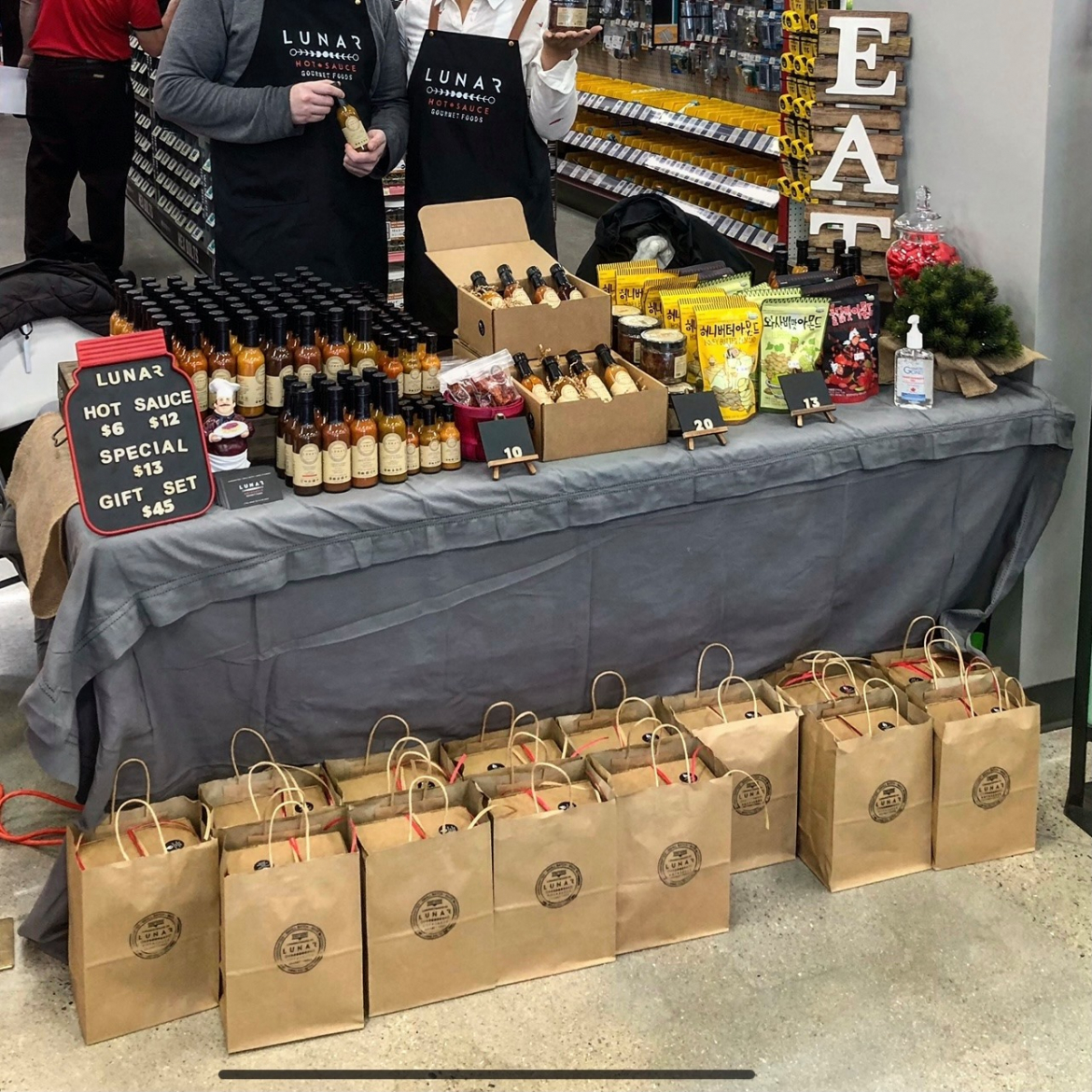 picture of Lunar hot sauce at a market with their products displayed on a table 