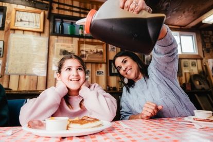 Mother pouring maple syrup for her daughter